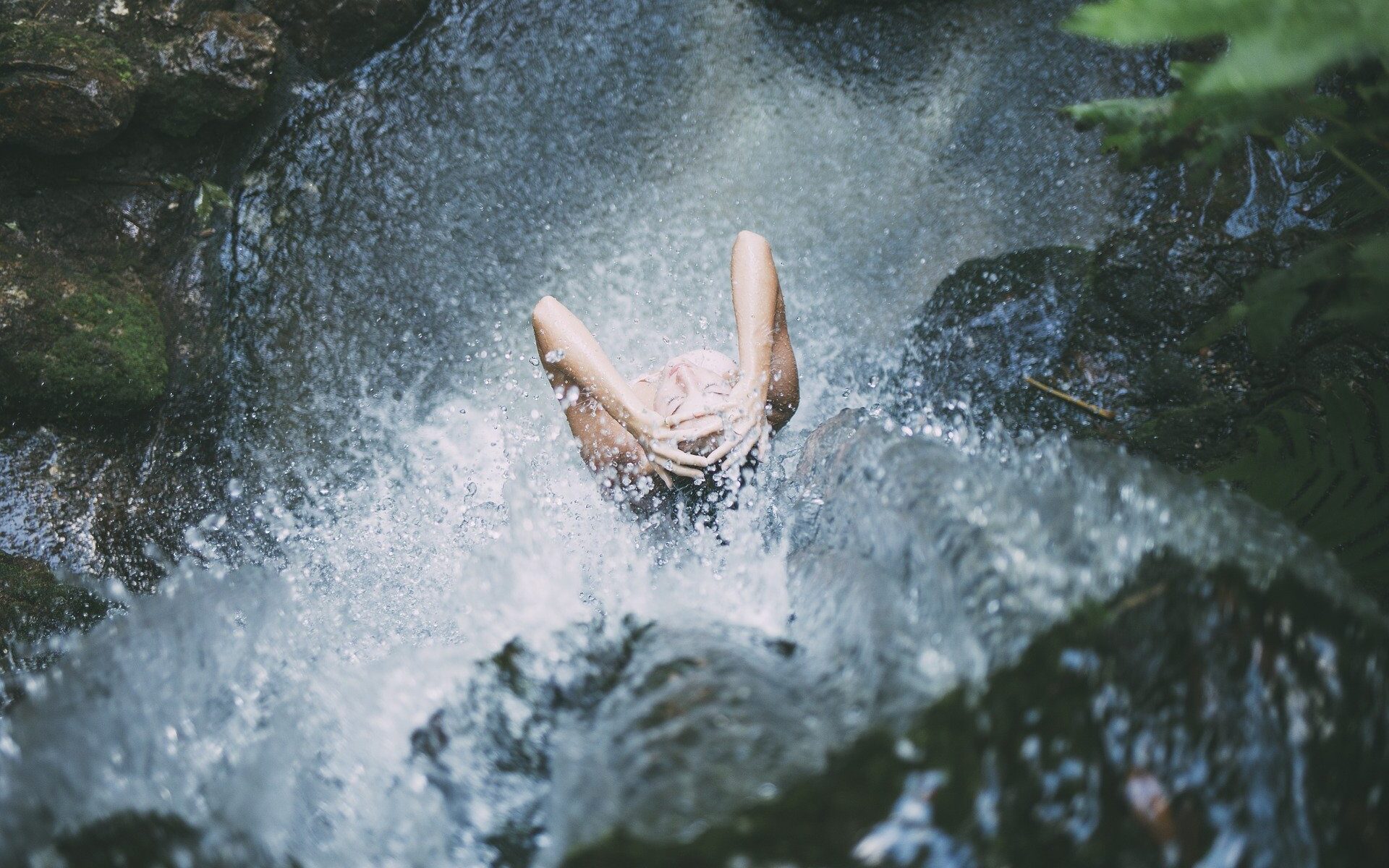Woman showering under waterfall.