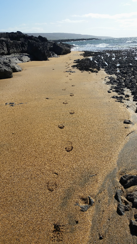 Footprints in wet sand at Fanore beach, County Clare, Ireland